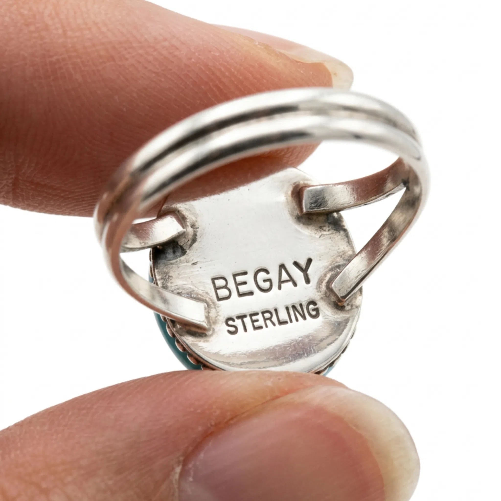 fingers holding a navajo kingman turquoise ring showing the back of the ring with BEGAY and STERLING on the back. 