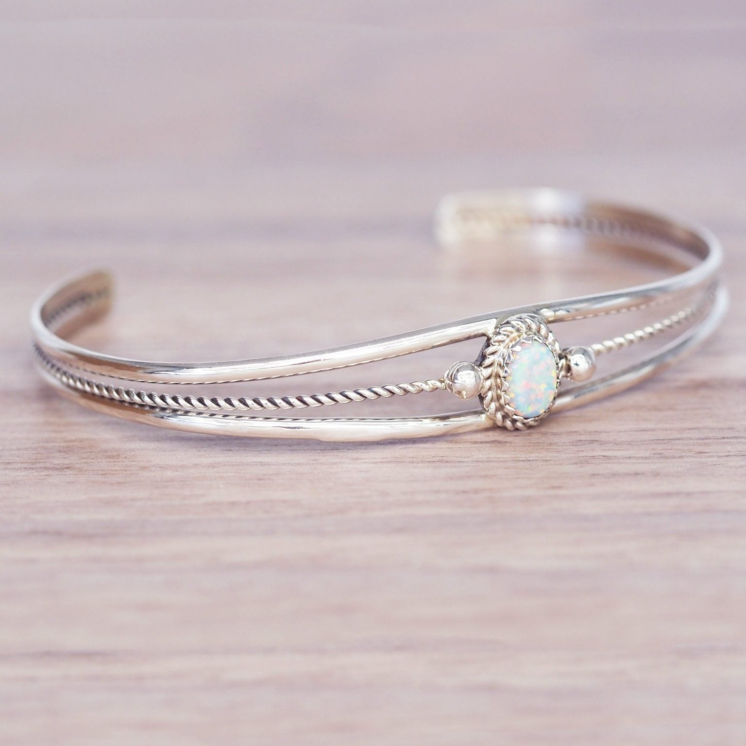 Silver bracelet with an opal stone on a wooden surface