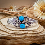 statement sterling Silver bracelet with turquoise stones on a wooden surface with flowers in the background