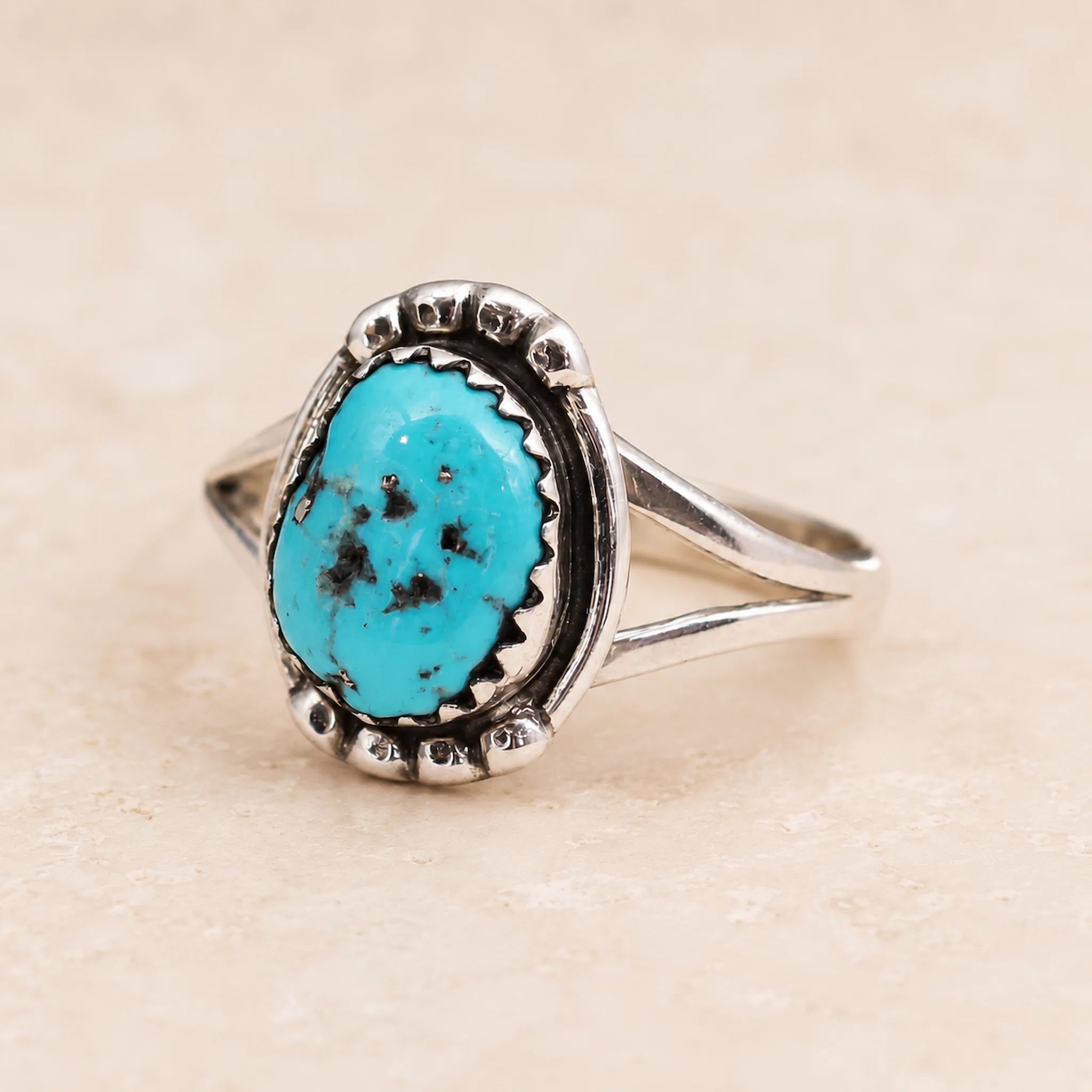 sterling Silver ring with a natural turquoise stone on a beige background which was hand crafted by navajo artisans