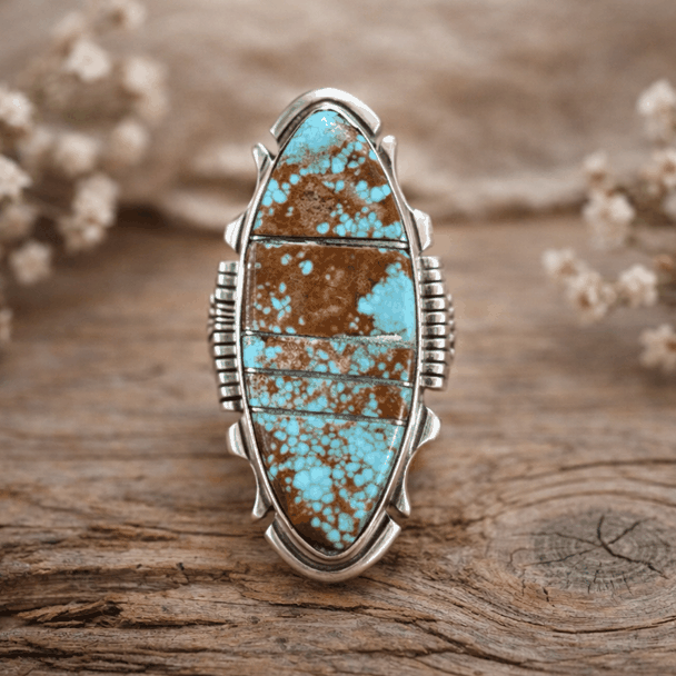 Turquoise stone ring with silver band on a wooden surface