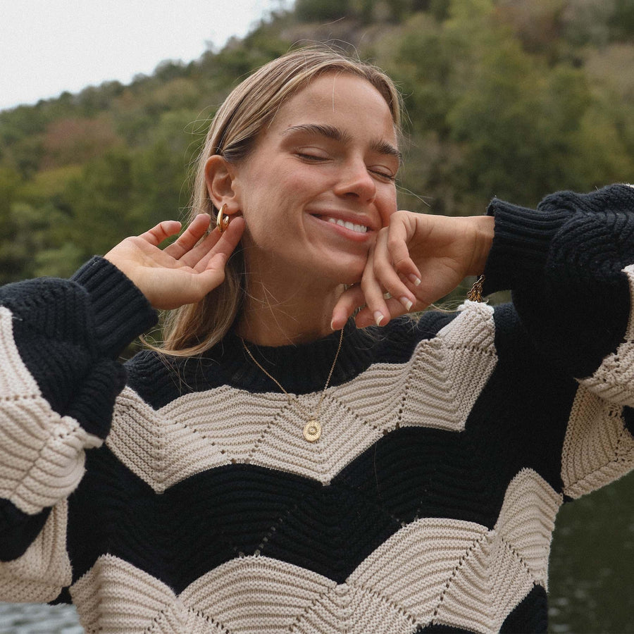 Smiling woman with black and white jumper wearing gold jewellery by Australian jewellery brand indie and harper