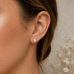 Close-up of an ear wearing a teardrop-shaped earring with a blurred background