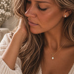 A close-up lifestyle shot of a woman wearing a october birthstone jewellery set featuring a delicate gold necklace with a teardrop-shaped natural opal pendant, paired with a matching opal stud earring.