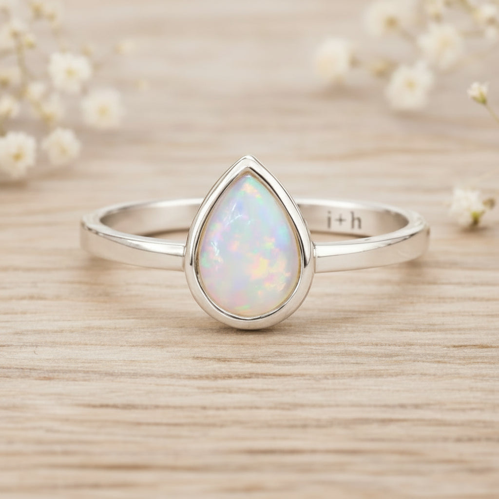 Sterling Silver October birthstone ring with pear-shaped natural opal gemstone on a wooden surface - birthstone jewellery gift