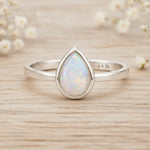 Sterling Silver October birthstone ring with pear-shaped natural opal gemstone on a wooden surface - birthstone jewellery gift