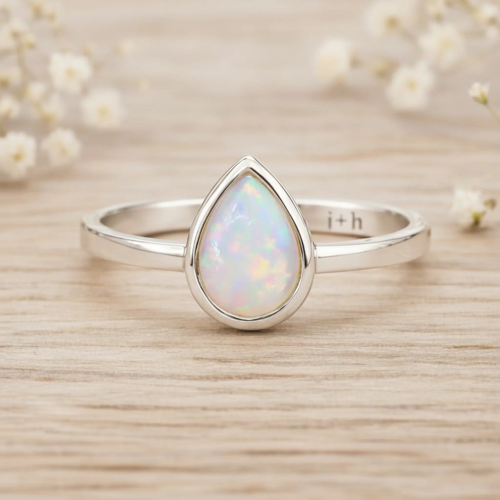 Sterling Silver October birthstone ring with pear-shaped natural opal gemstone on a wooden surface - birthstone jewellery gift