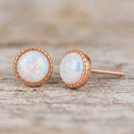 One opal stud facing forward and one angled on rustic wood