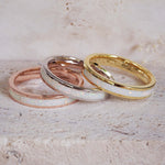 Three rings with white opal interior designs on a beige surface