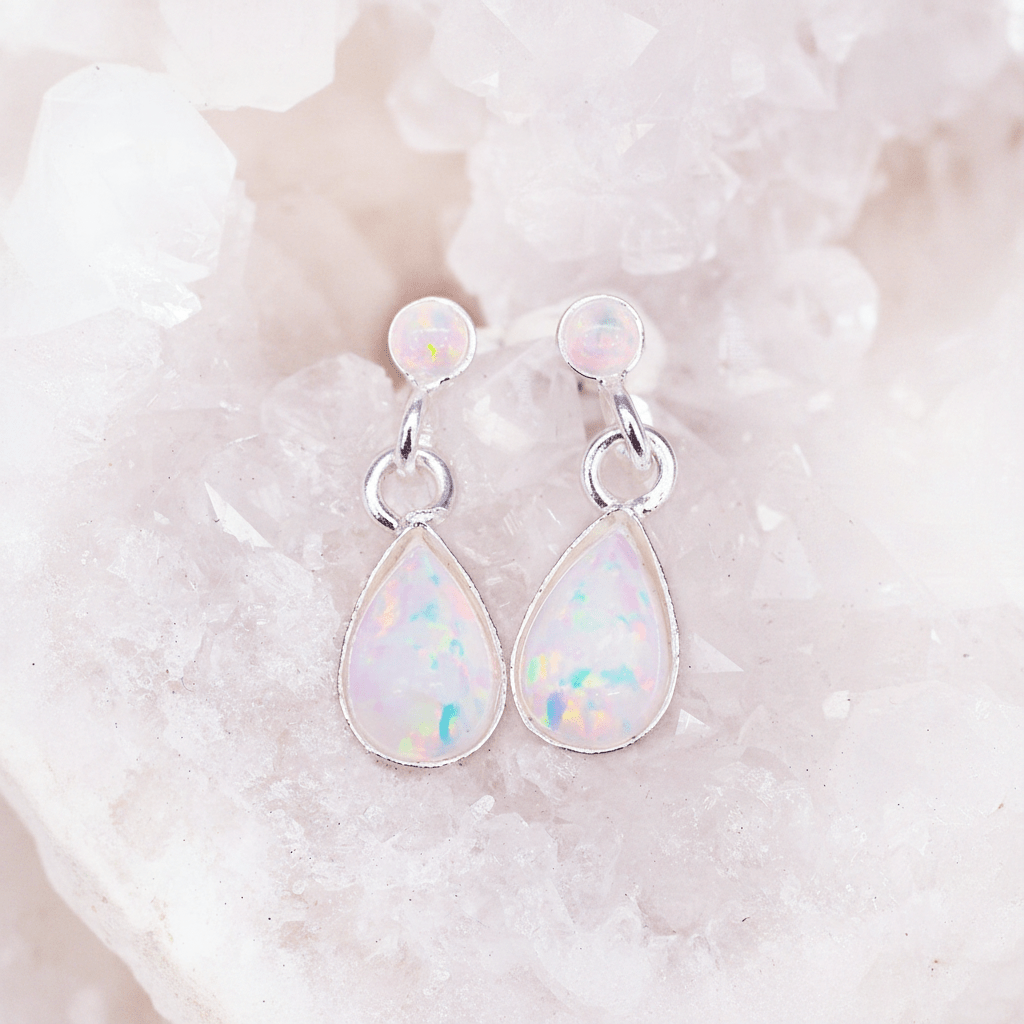 Teardrop-shaped opal earrings on a textured white background