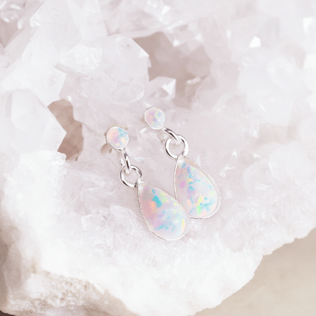 Opal teardrop earrings on a white stone background