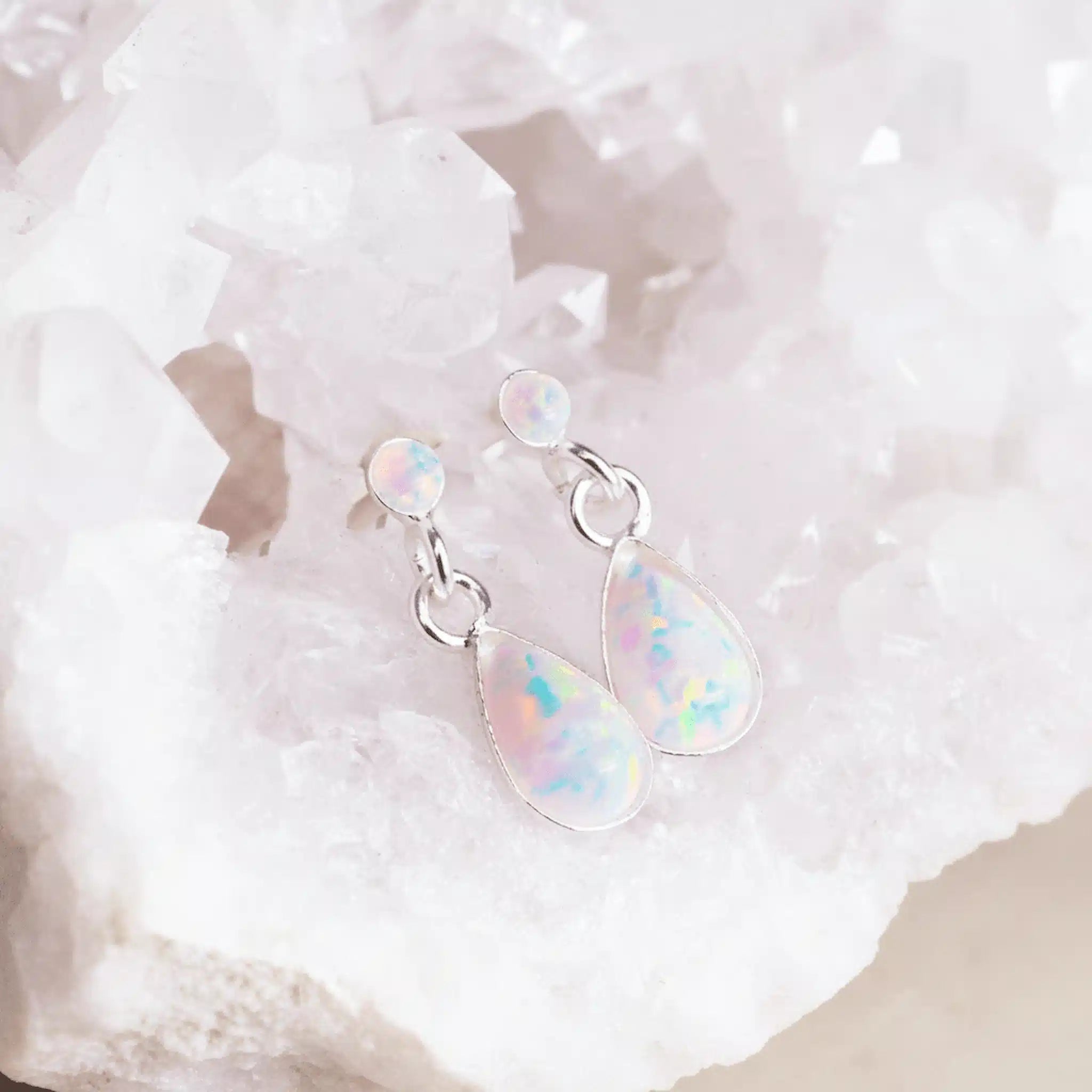 Opal teardrop earrings on a white textured background