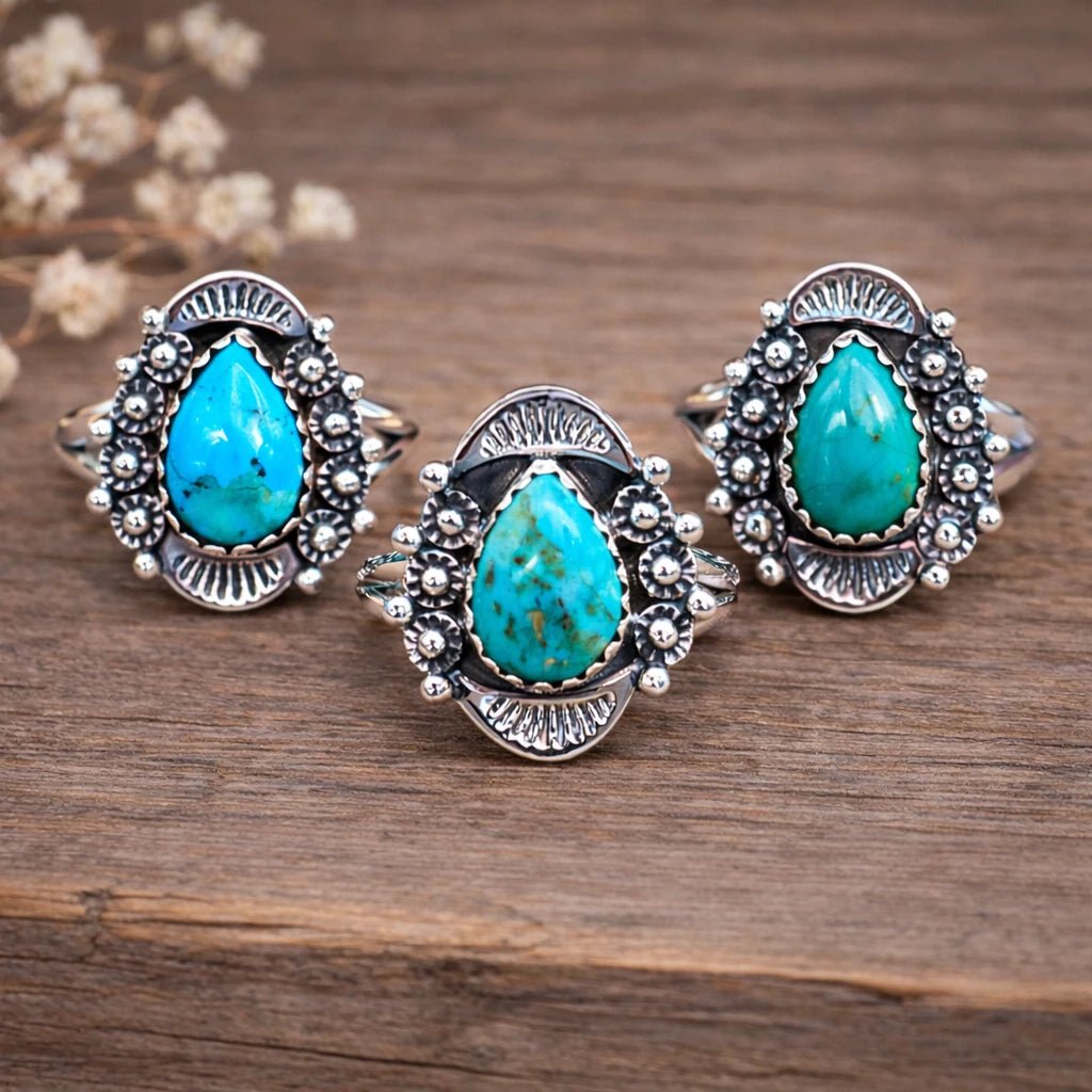 Three sterling silver rings with natural turquoise stones on a wooden surface