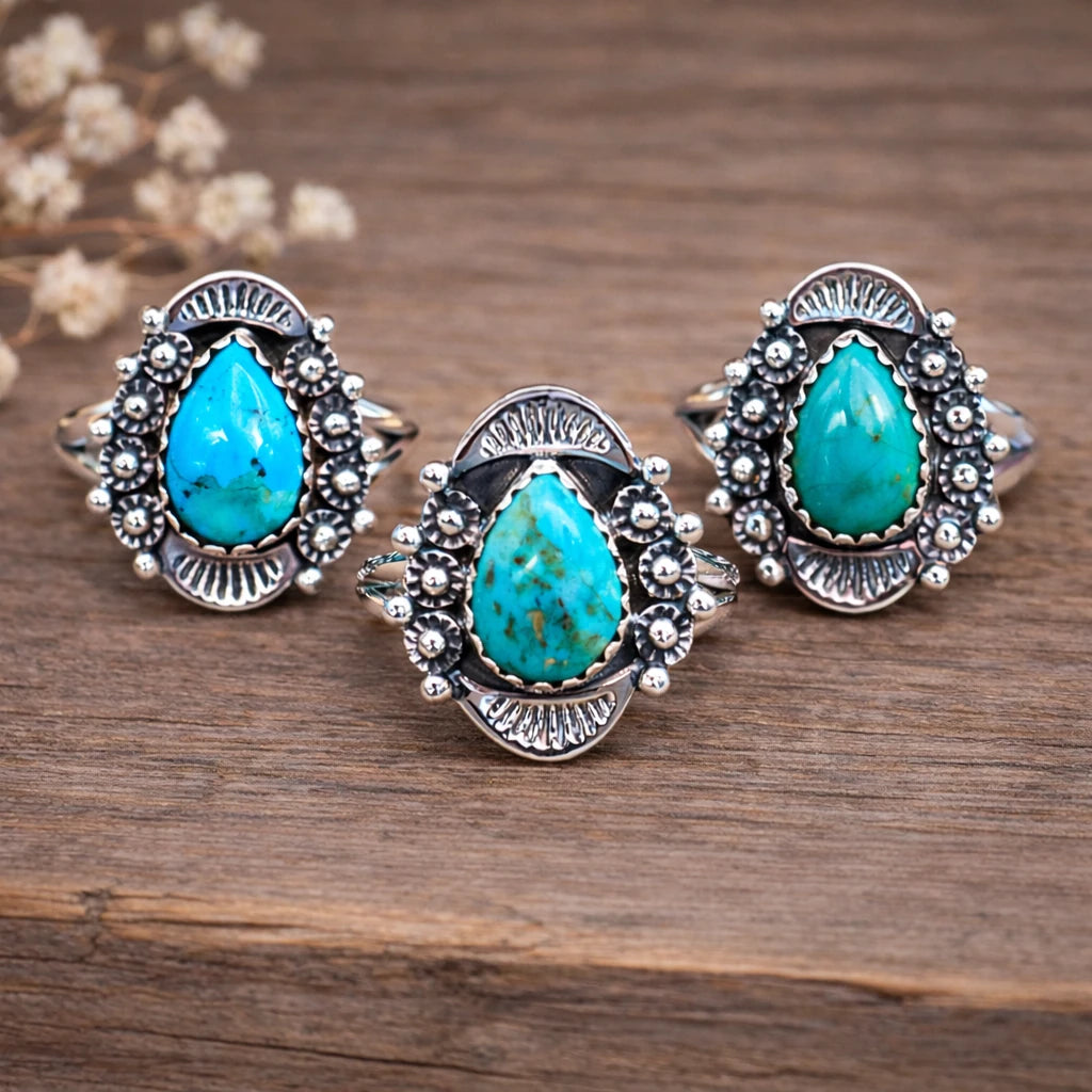 Three sterling silver rings with natural turquoise stones on a wooden surface