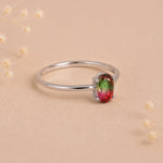side view of a sterling silver oval watermelon tourmaline ring with green and pink colours on a light background