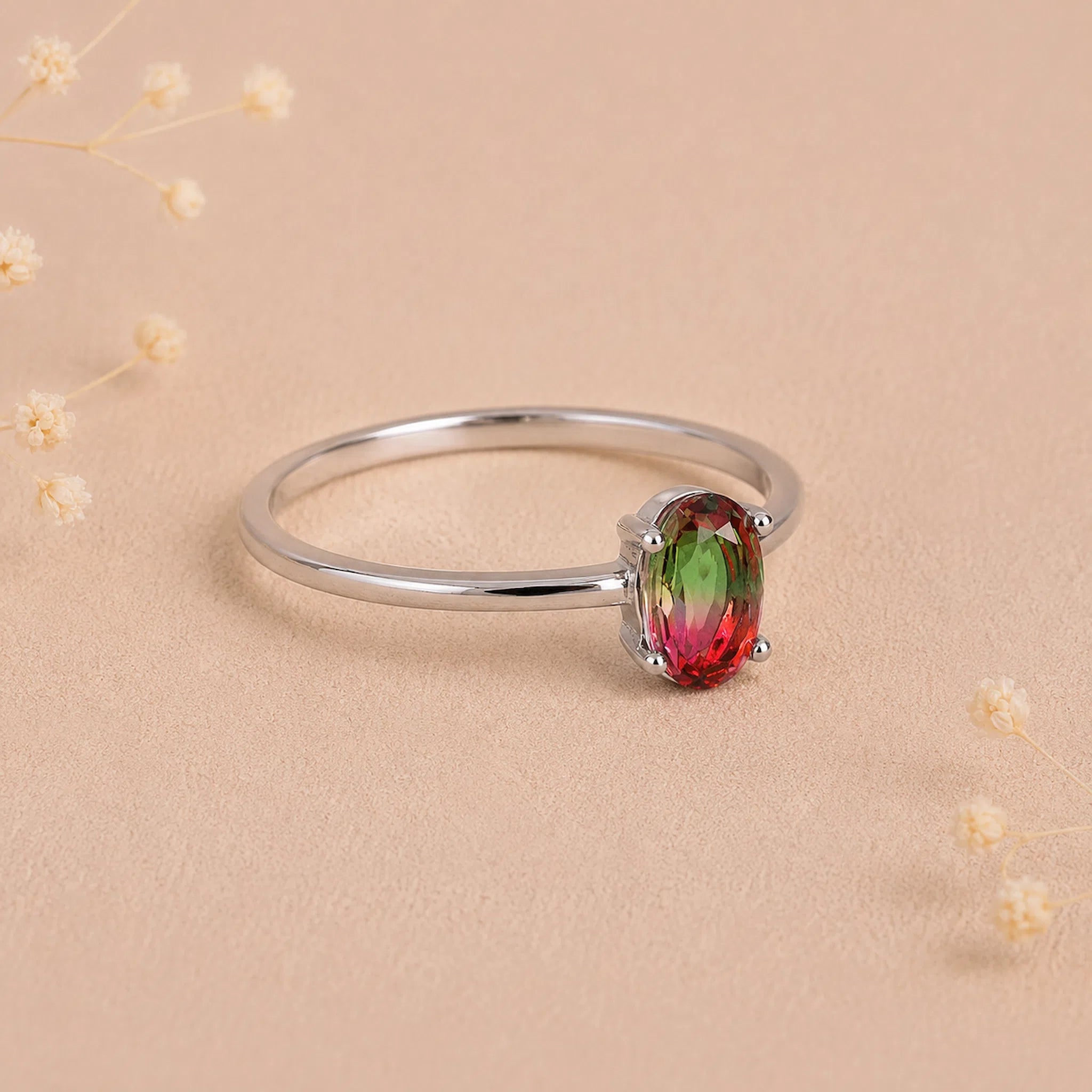 side view of a sterling silver oval watermelon tourmaline ring with green and pink colours on a light background