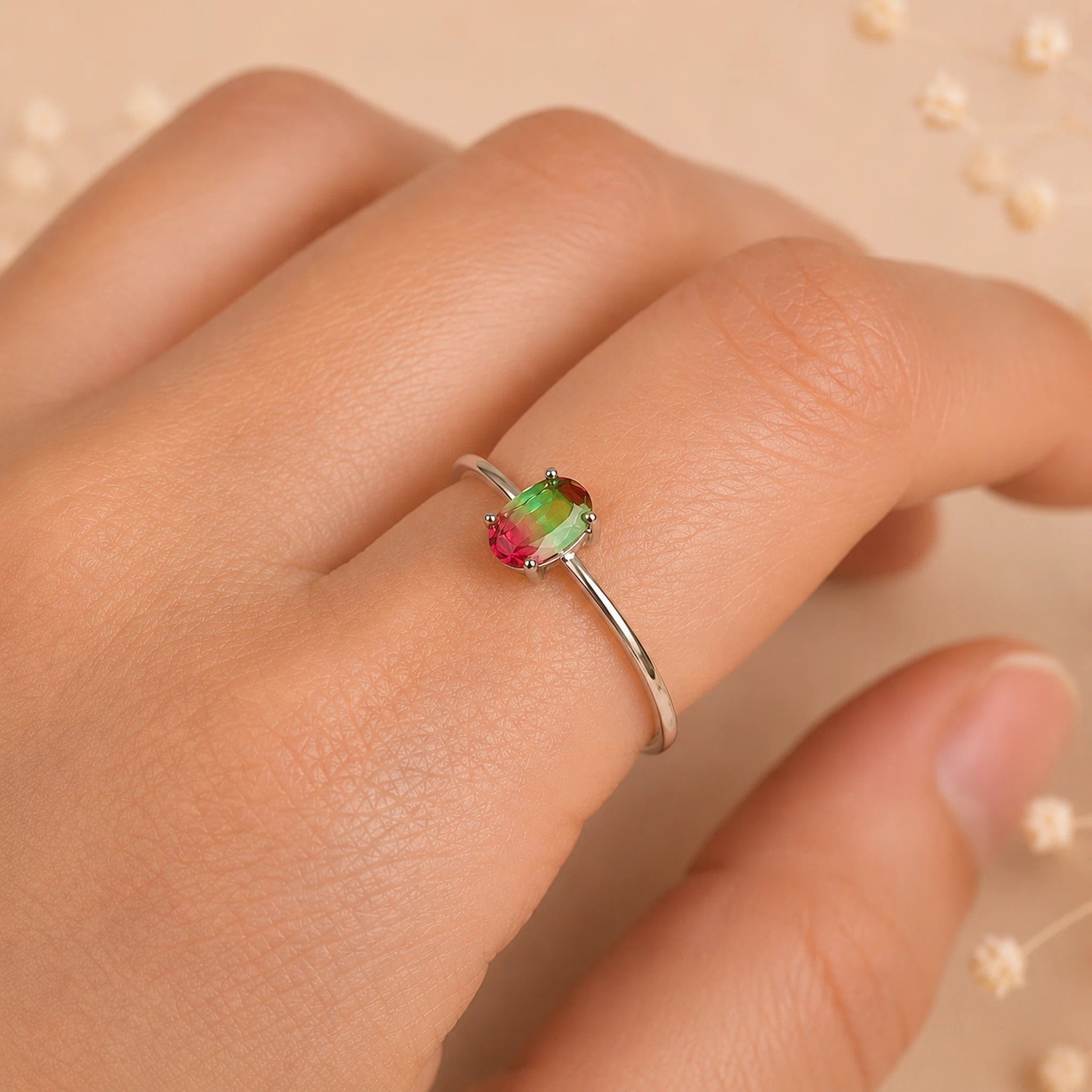 sterling silver oval watermelon tourmaline ring with green and pink colours worn on a finger against a light background