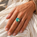 Peacock Dahlia Turquoise Heart Ring worn on a hand resting on a white linen dress