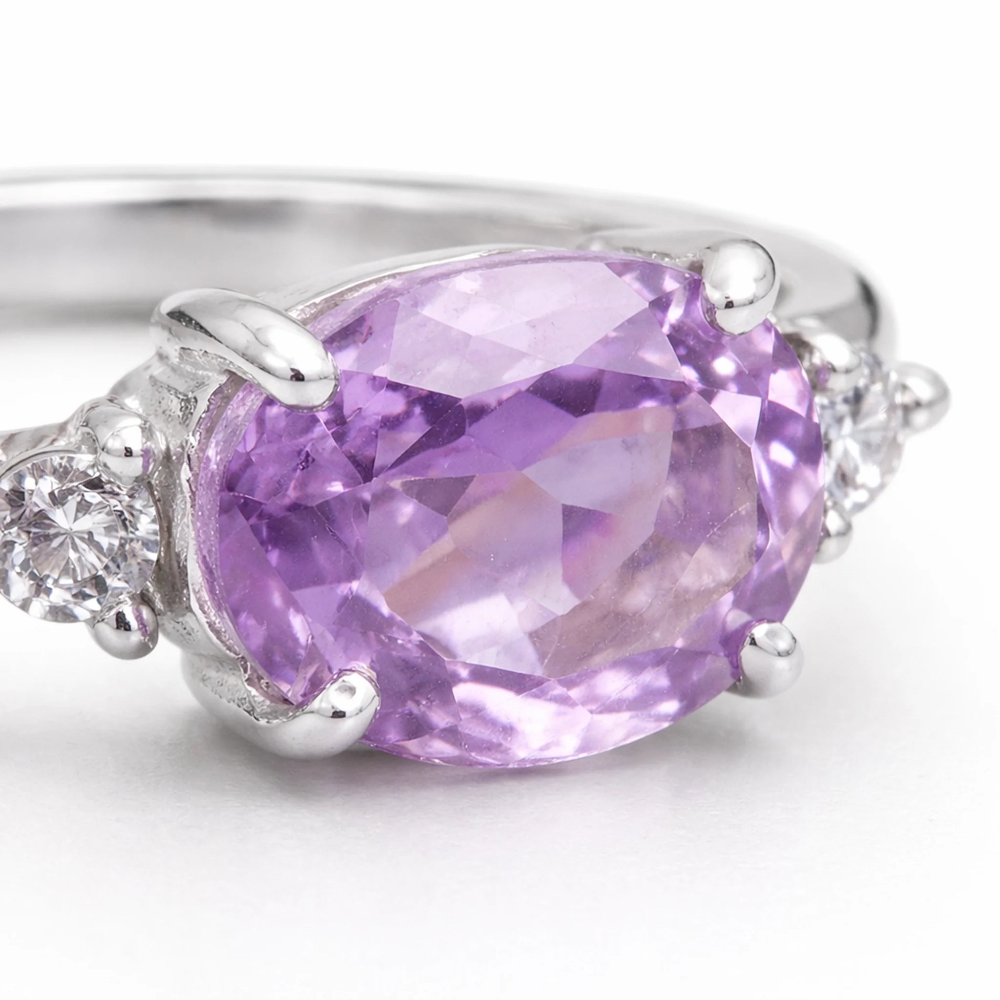 Ring with a faceted natural purple pink amethyst gemstone and sterling silver setting on a white background
