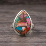 Pink copper turquoise ring front view, pink, turquoise and green stone in a sterling silver bezel on dark wood