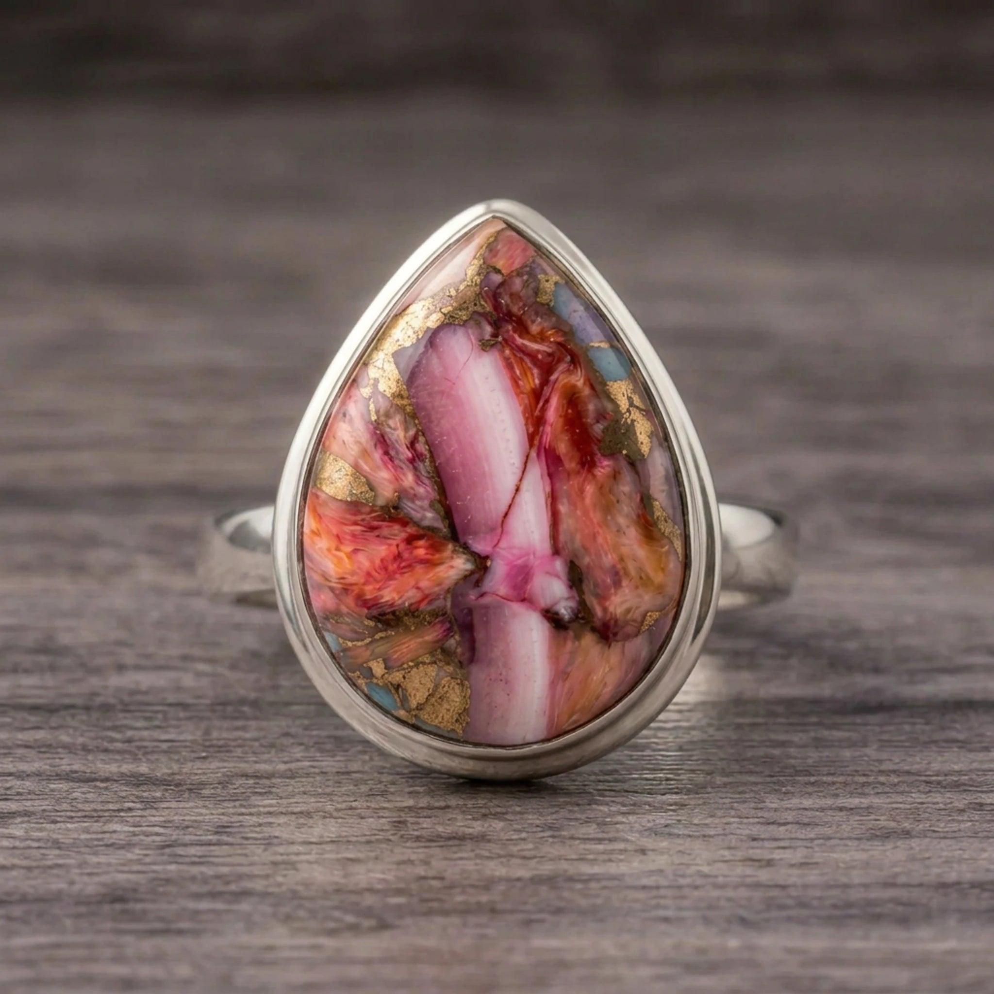 Pink copper turquoise ring front view, pink, orange and white teardrop stone in sterling silver on dark wood