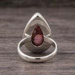 Back of the pink copper turquoise ring showing the open-back sterling silver bezel and band on dark wood