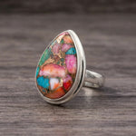 Pink copper turquoise ring side view, teardrop stone bezel set in sterling silver, lying on dark wood