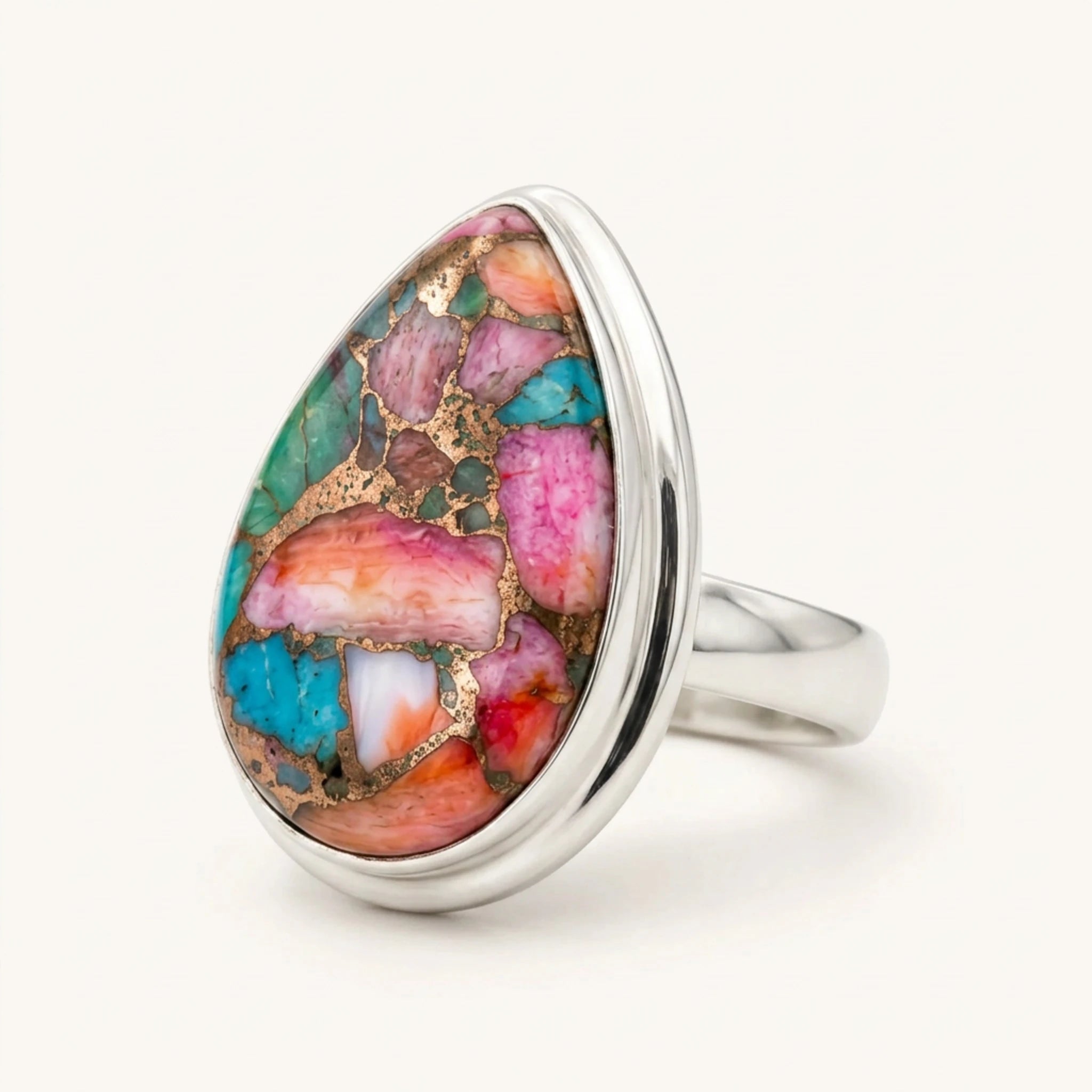 Pink copper turquoise ring three-quarter view, multicoloured teardrop stone in sterling silver on cream