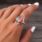 Close-up of a pink copper turquoise ring worn on the hand, sterling silver bezel and band, dark wood