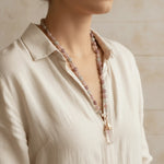 Person wearing a necklace with pink beads against a neutral background