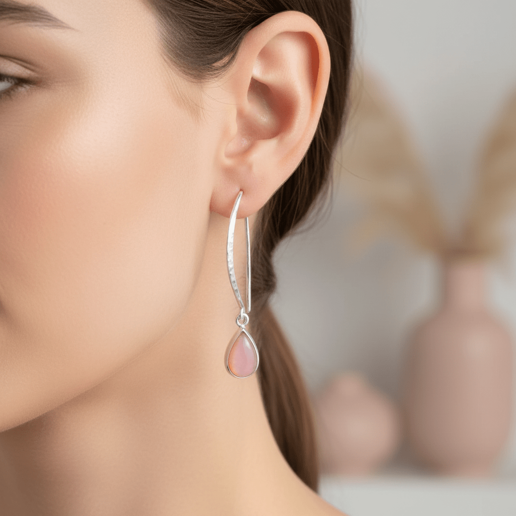 Close-up of a woman wearing pink teardrop earrings with a blurred background