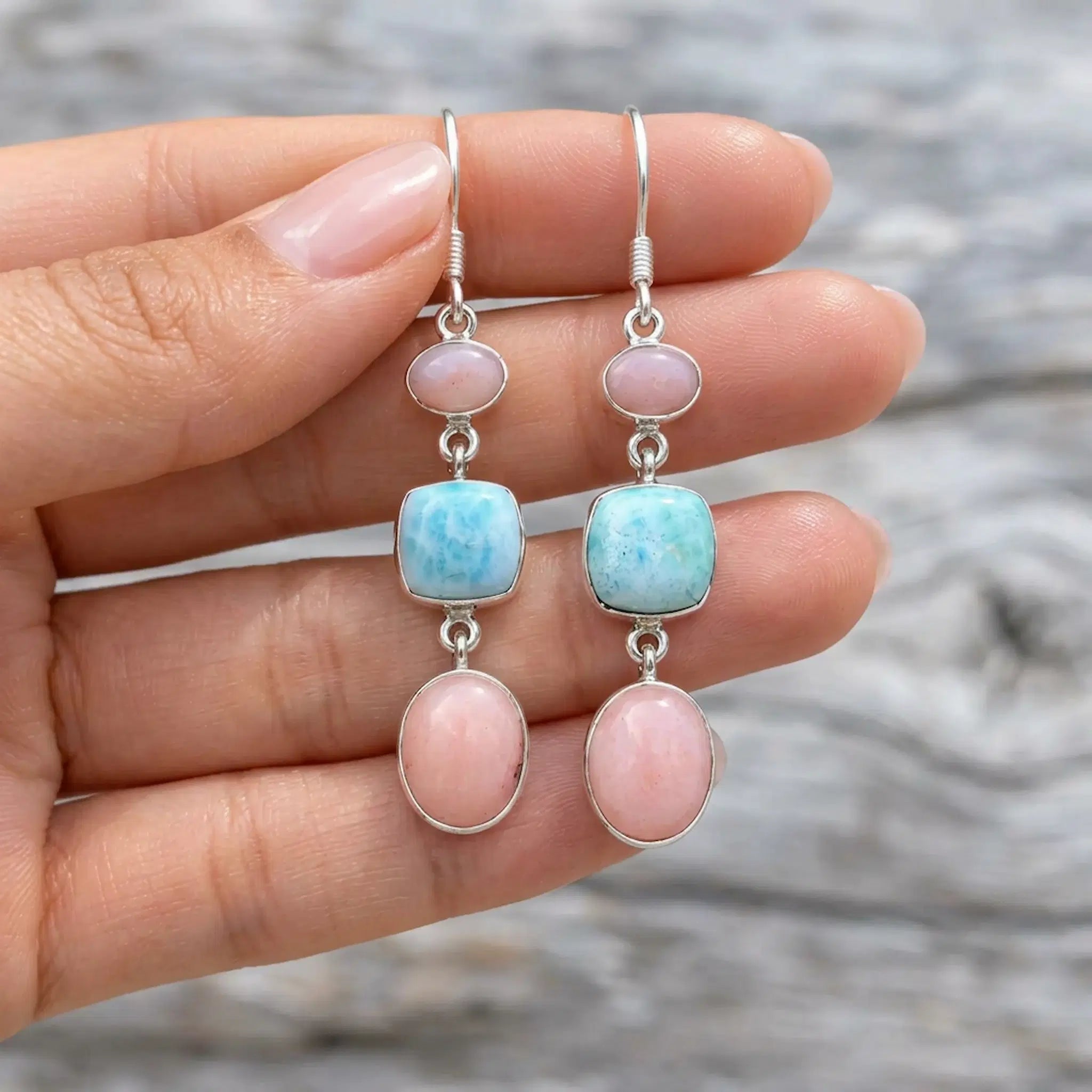 Pink opal and larimar French hook earrings held over fingers to show their size