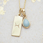 Gold necklace with a March Birthstone aquamarine pendant and a Pisces Zodiac Star Sign symbol on a textured background