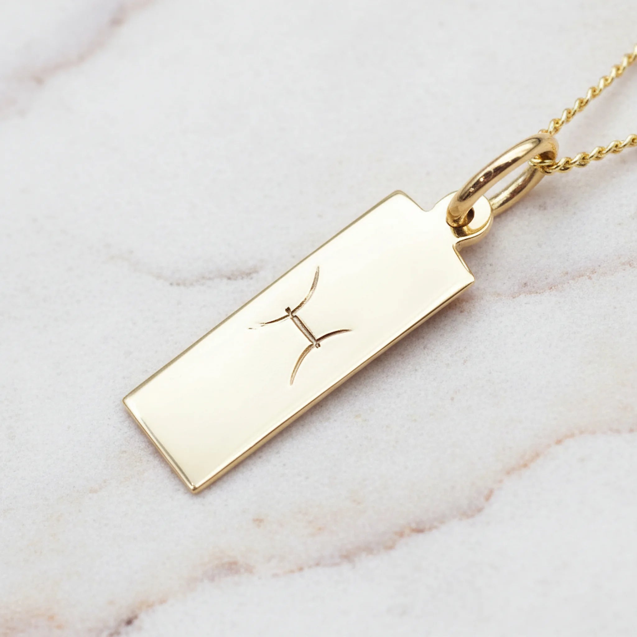 Gold Chain Necklace, featuring a pendant with a hand drawn Pisces Zodiac Star Sign symbol on a marble background