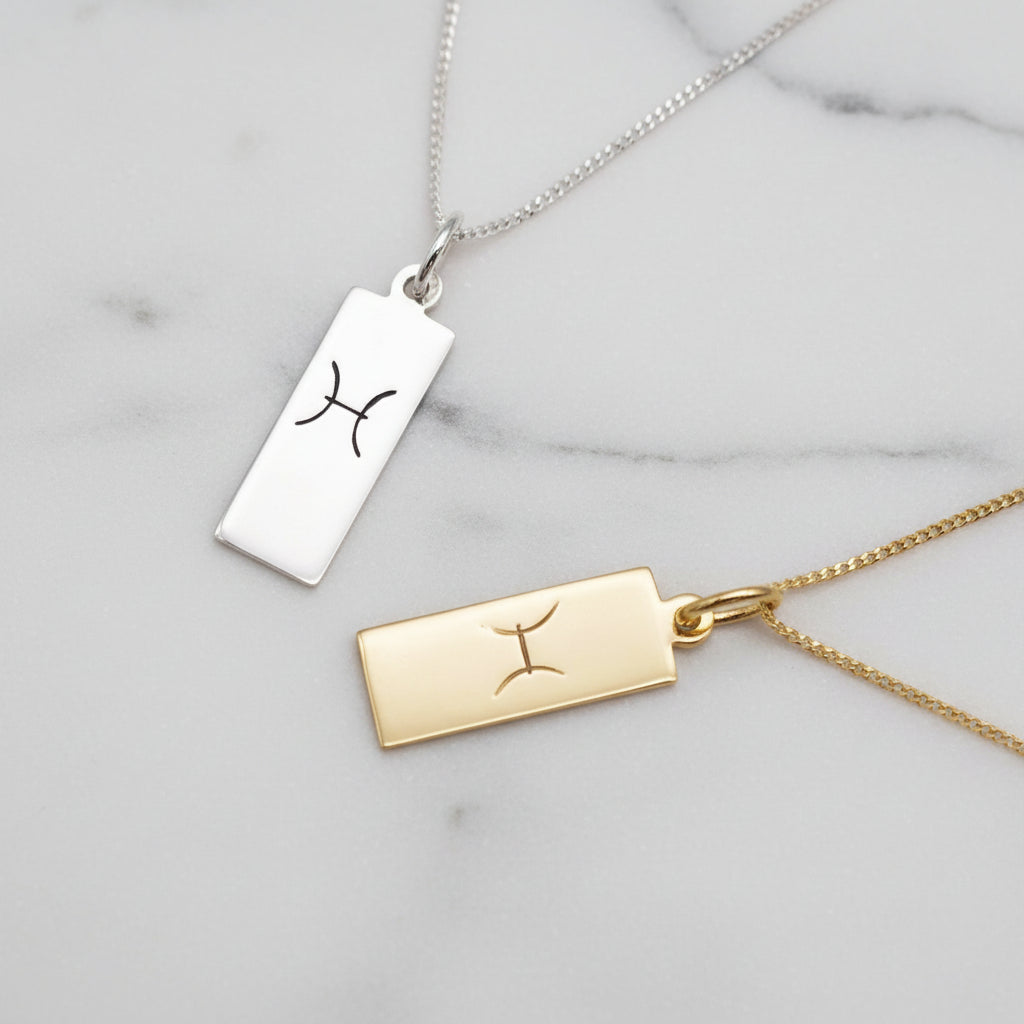 pisces zodiac necklaces in sterling silver and gold plated sterling silver on a white stone surface