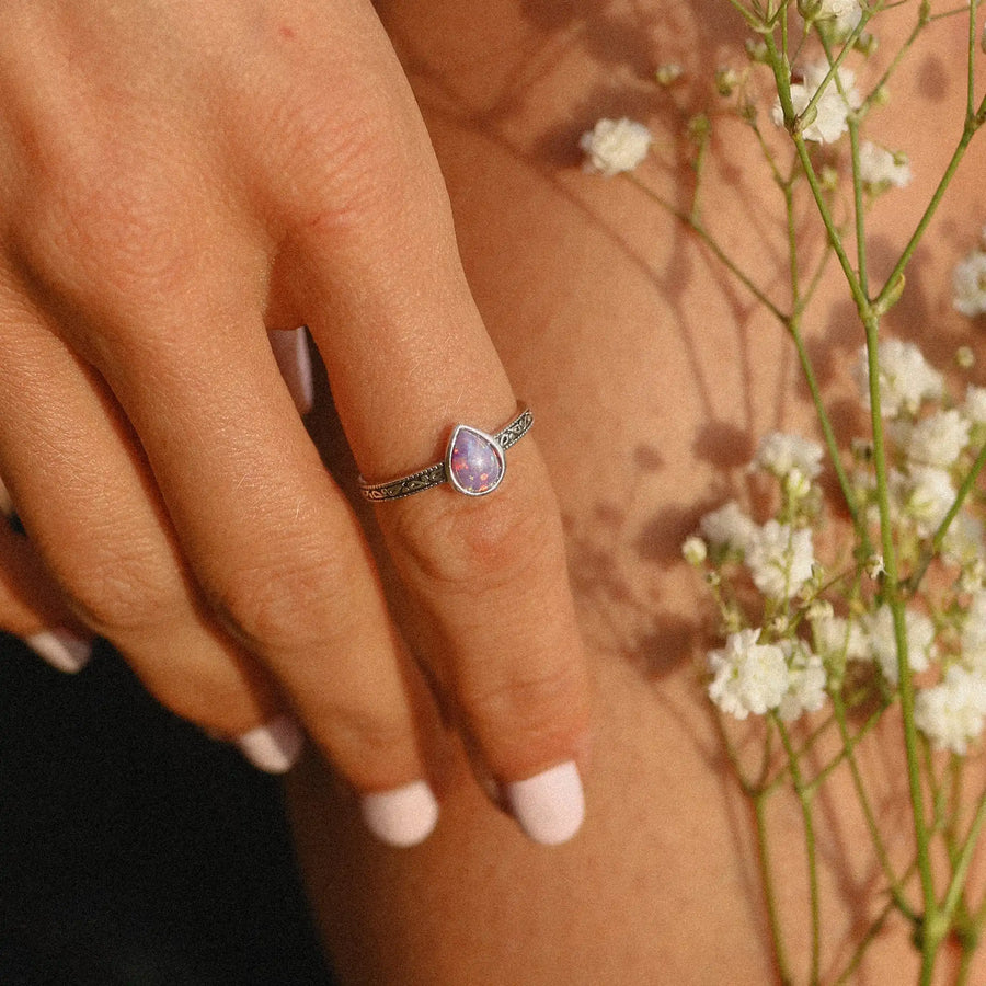 woman wearing sterling silver ring with purple teardrop shaped opal stone
