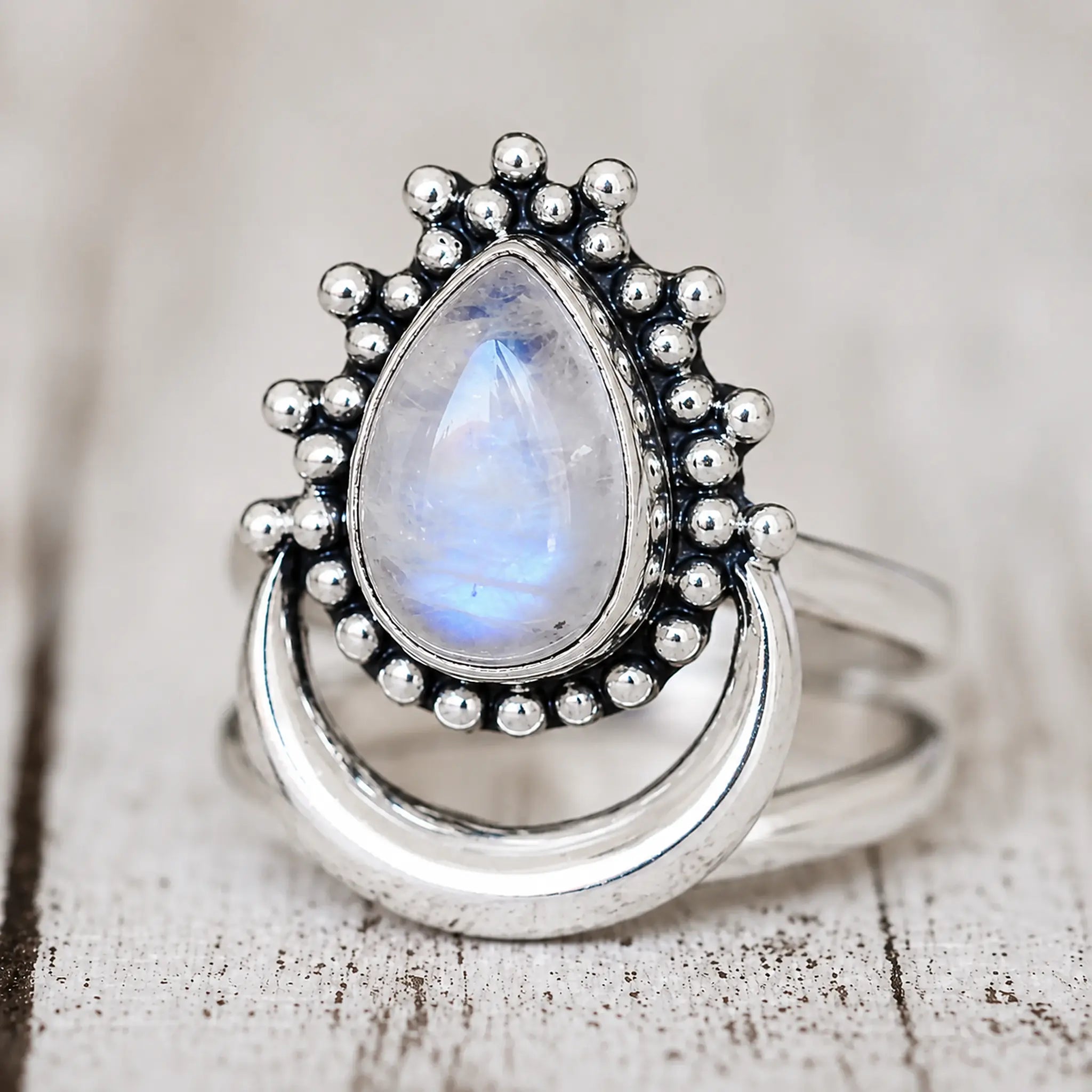 Angled view of a rainbow moonstone crescent ring in polished sterling silver with beaded detailing