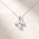 Rainbow moonstone leaf necklace flat lay on warm white linen, three pear-shaped moonstones on a fine silver curb chain