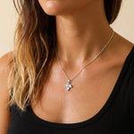 Rainbow moonstone leaf necklace worn on a model in a black singlet, dainty pendant on a fine silver curb chain