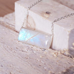 sterling silver Necklace with a rectangular natural rainbow moonstone pendant on a textured surface