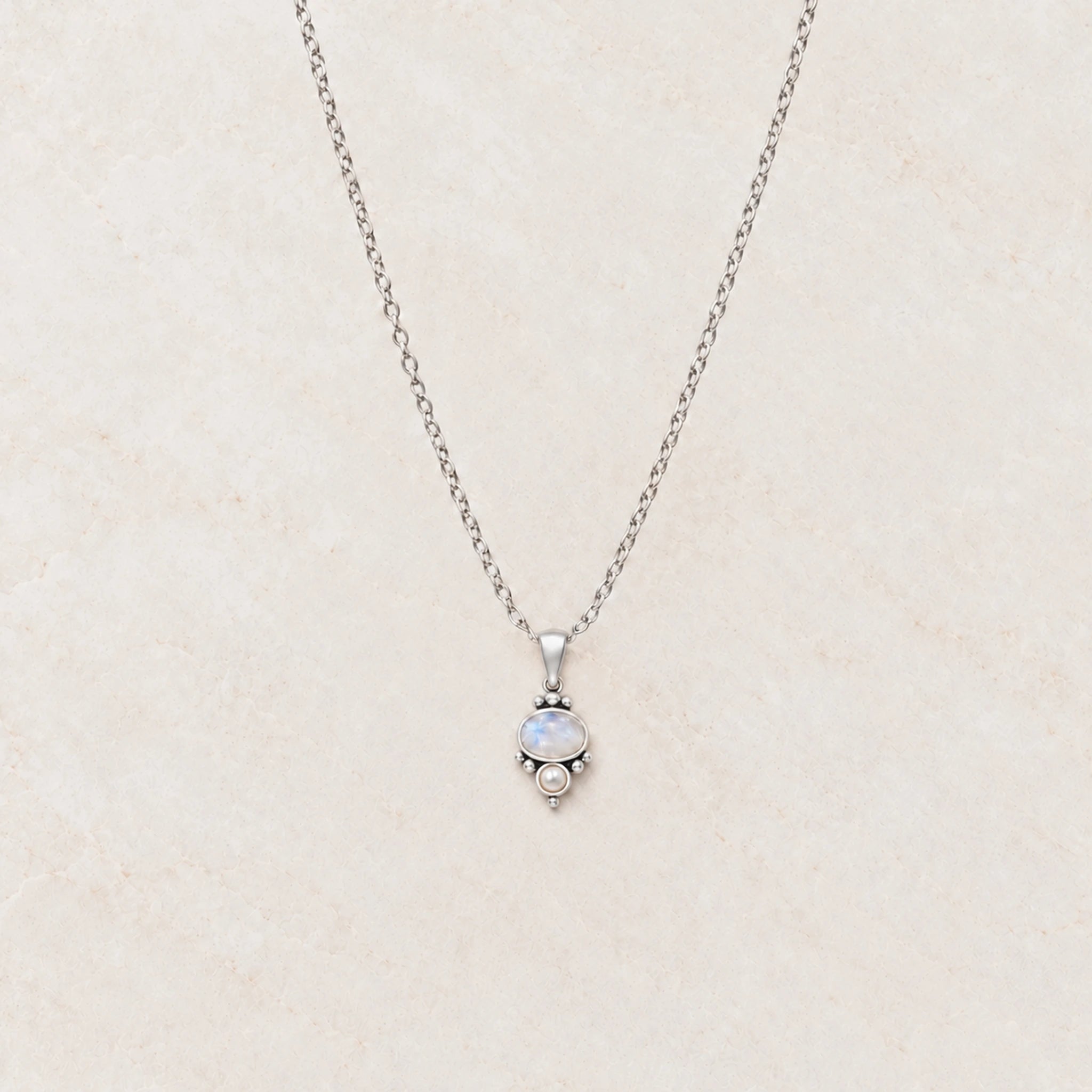 Rainbow moonstone and pearl necklace flat lay on cream marble showing the full fine sterling silver chain