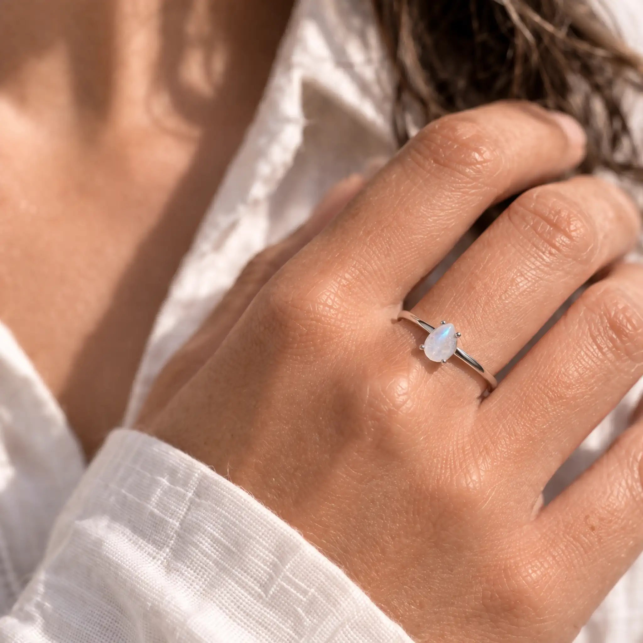 hand wearing a sterling silver rainbow moonstone ring