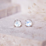 Pair of sterling silver stud earrings with a natural rainbow moonstone gemstones on a light background