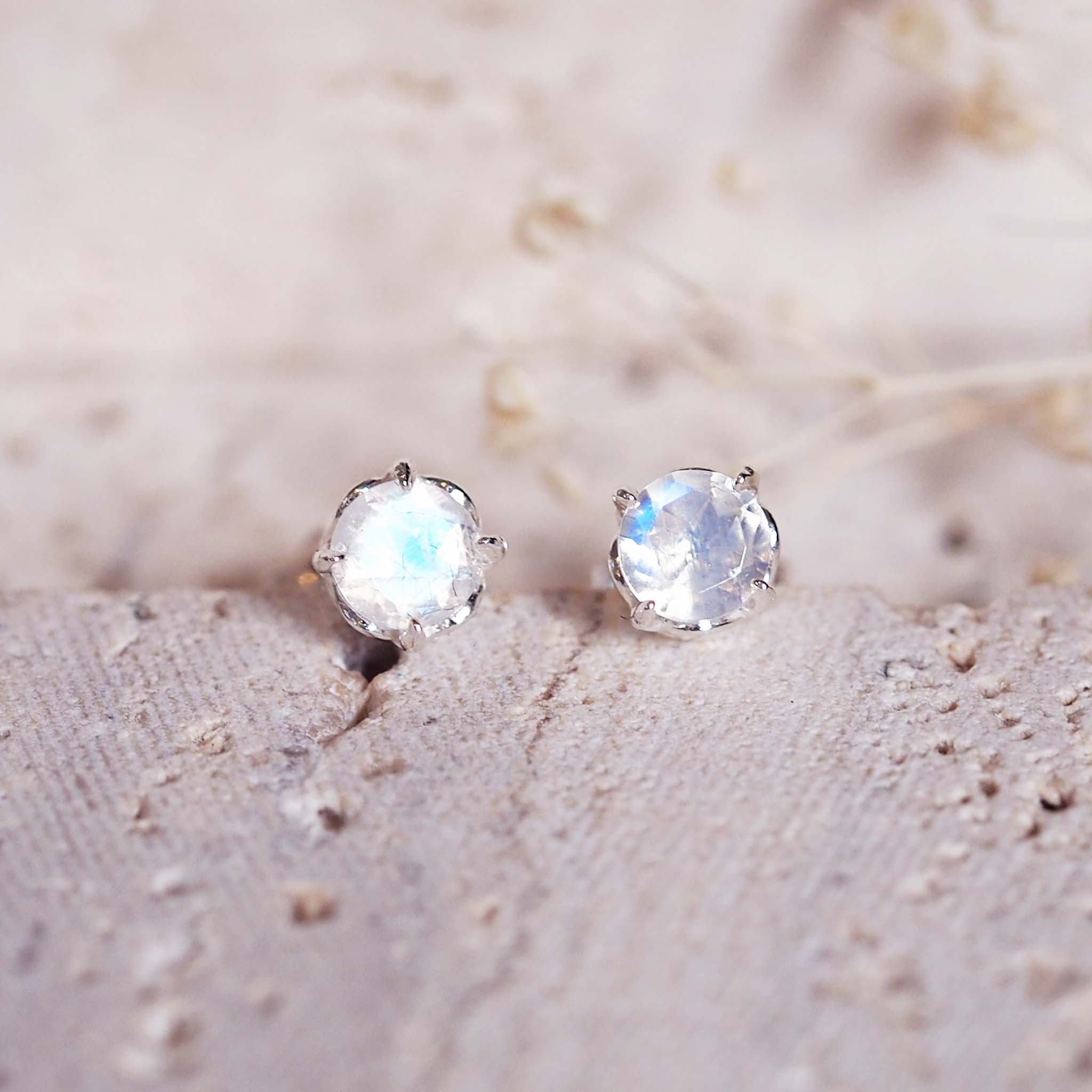 Pair of sterling silver stud earrings with a natural rainbow moonstone gemstones on a light background