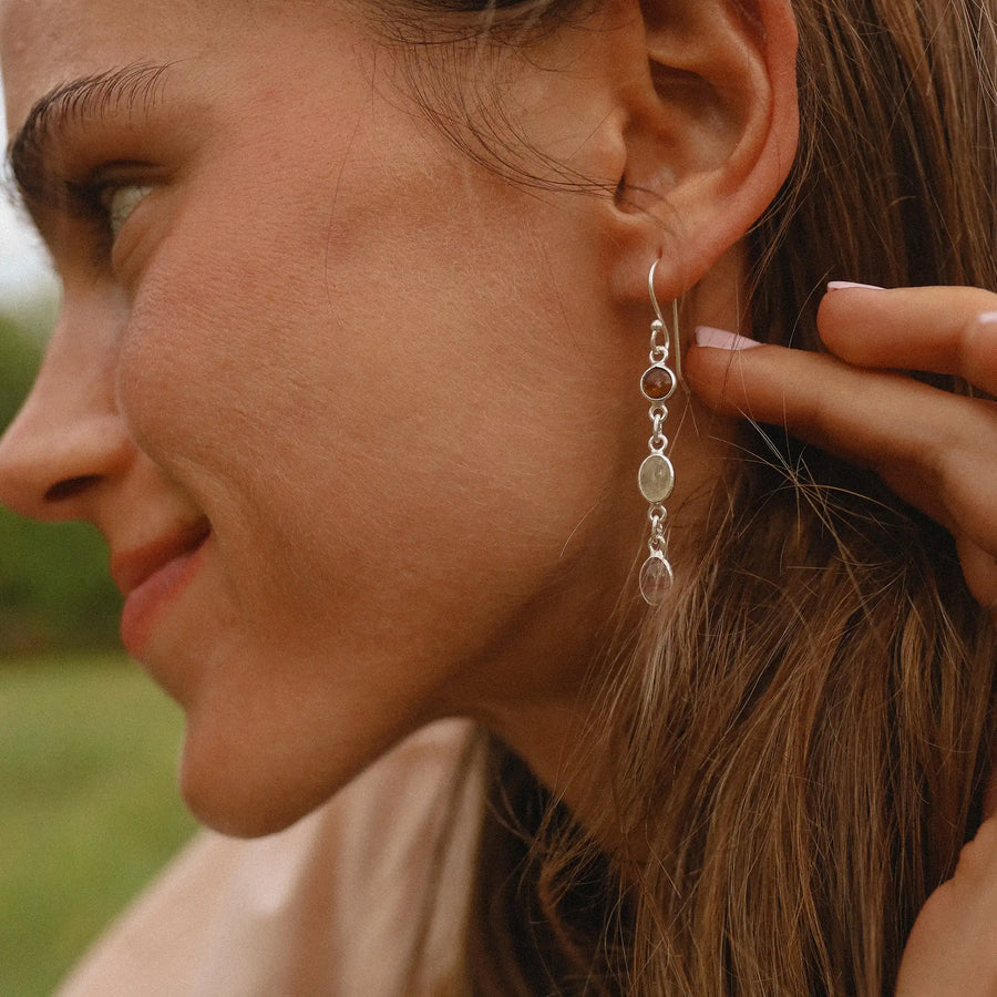woman wearing drop earrings with three rainbow tourmaline stones