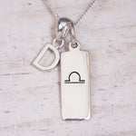sterling silver initial d libra zodiac star sign pendant necklace against a light wooden background