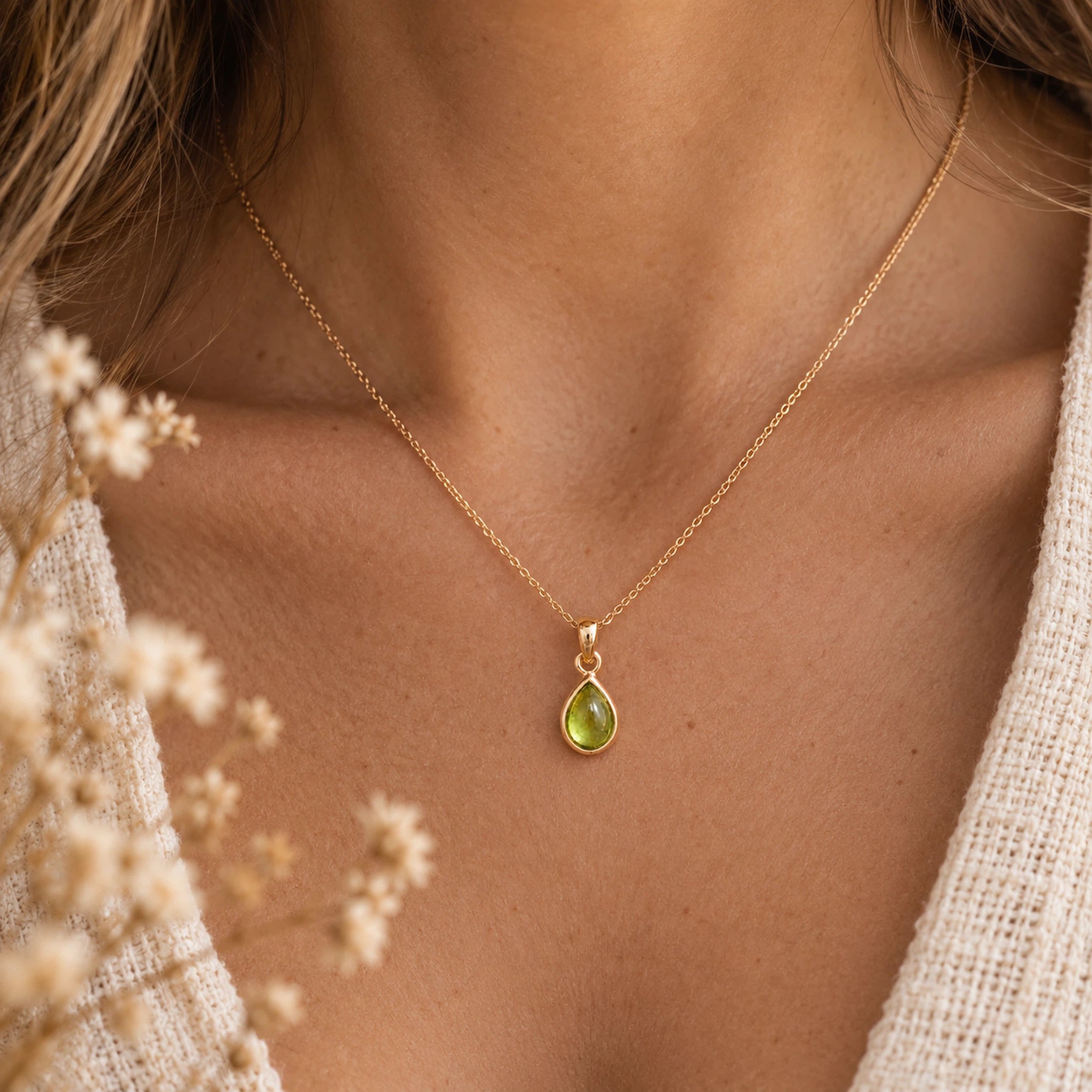 close up of a woman wearing a rose gold august birthstone necklace featuring a natural peridot pendant