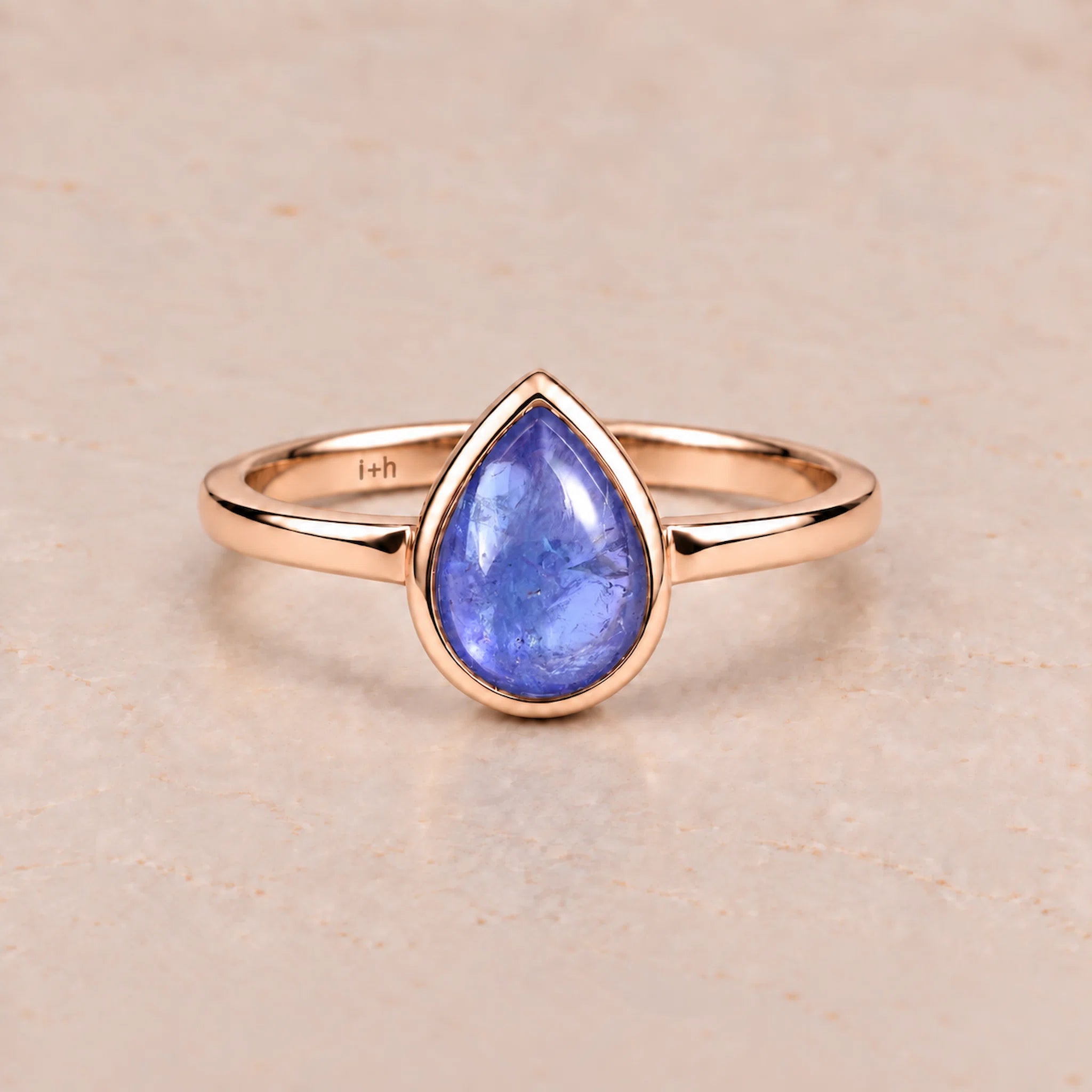 Rose gold december birthstone ring with a blue teardrop-shaped natural tanzanite gemstone on a light background
