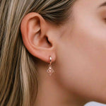 Close-up of a woman wearing a rose gold hoop earring with a delicate lotus flower charm design.