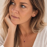 model wearing rose gold january birthstone earrings and matching necklace made with natural garnet gemstones
